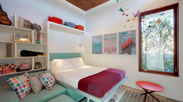 A bedroom with a bed and desk in a room