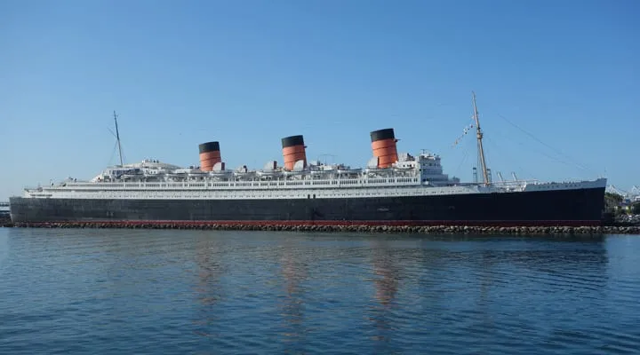 A large ship in a body of water with RMS Queen Mary in the background