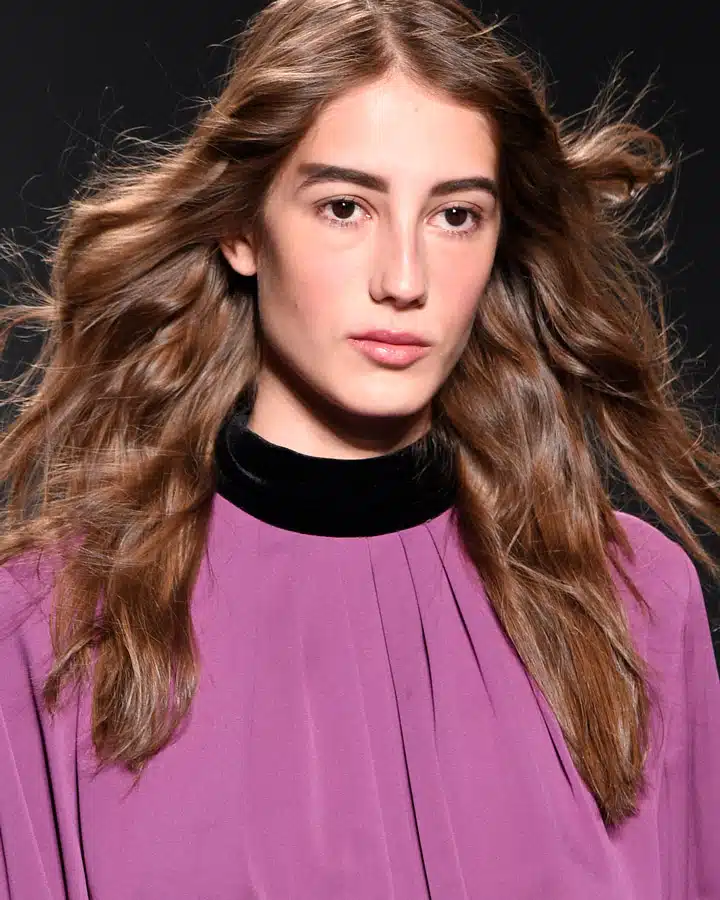 A close up of a woman wearing a purple shirt