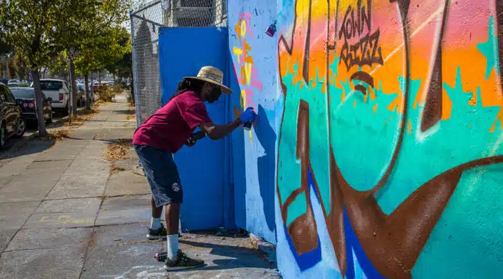 A man standing next to a graffiti covered wall