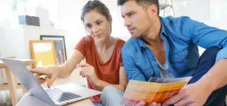 A man and a woman sitting at a table using a laptop