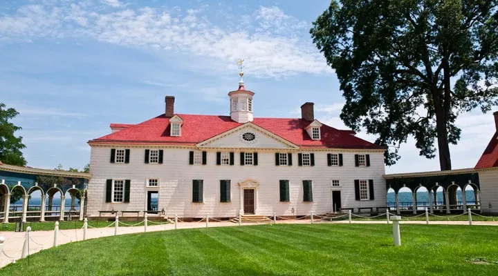 A small clock tower in the middle of a field with Mount Vernon in the background