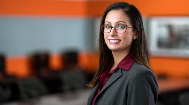 A woman wearing glasses and smiling at the camera