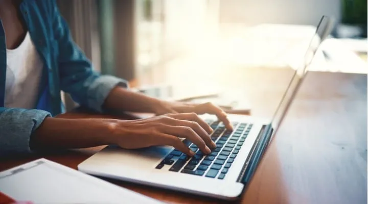 A person using a laptop computer sitting on top of a table