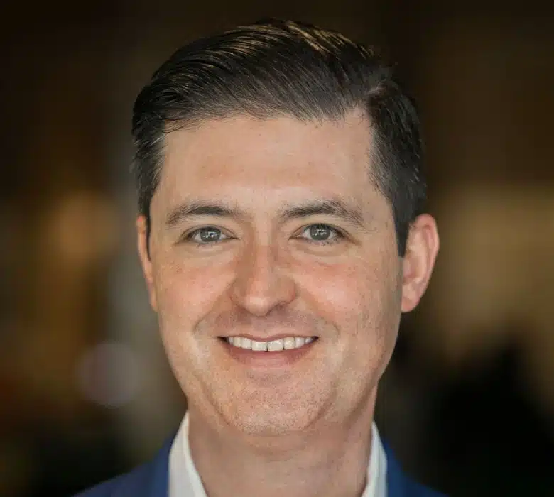 A man wearing a suit and tie smiling and looking at the camera