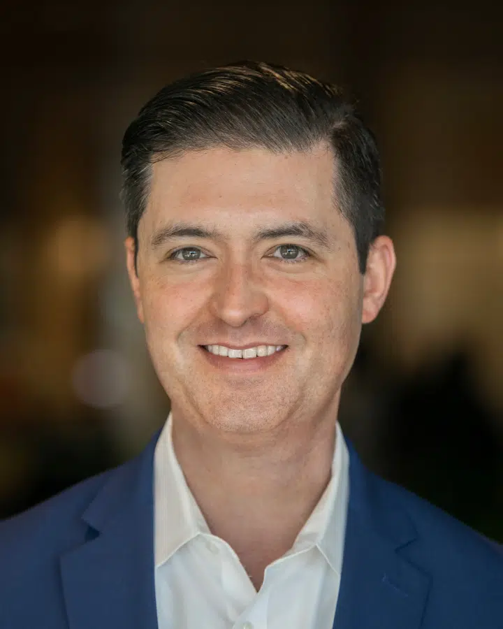 A man wearing a suit and tie smiling and looking at the camera